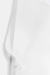 Camiseta oversize de cuello redondo y manga larga con puños abotonados. Confeccionada en algodón, presenta un diseño con combinación de tejidos a tono y bajo asimétrico.