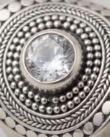 Anillo de plata 925 con diseño circular labrado y cristal central. Presenta un estilo étnico con detalles de puntos en relieve alrededor del centro.