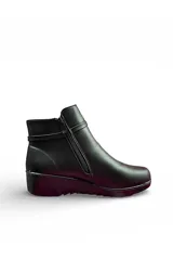 Bota corta de cuero negro, con taco cuadrado bajo y punta redondeada. Presenta una tira decorativa con hebilla metálica redonda y pedrería en el lateral exterior, además de cierre lateral interno.