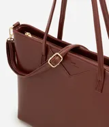 Cartera tipo shopper grande de Satinato, confeccionada en poliuretano con textura efecto crocco en color marrón. Presenta doble asa fija, correa larga desmontable con herrajes dorados y cierre superior por cremallera.
