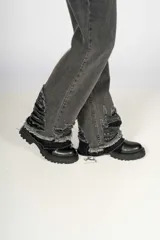 Pantalón de jean gris oscuro de corte wide leg con roturas y desgaste en el ruedo y las piernas.