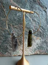 Aros de tipo argolla grande fabricados en metal dorado, con un dije colgante de piedra natural en bruto.