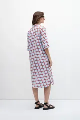 Maxi vestido camisero celeste con estampado geométrico de cuadrados rojos, mangas cortas y aberturas laterales.