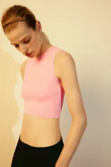 Top crop de tejido de punto color beige claro, con cuello redondo y manga sisa. Presenta acabados en rib en el cuello, sisas y bajo.