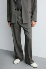 Pantalón de vestir con corte flare y ajuste relajado, confeccionado en tejido con viscosa y patrón de espiga. Cuenta con bolsillos frontales, bolsillos traseros de vivo y cierre frontal con cremallera y botón.