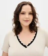 Blusa de viscolycra color beige con escote en V y cuello doble en tono negro con borde de ondas, de mangas cortas y corte amplio.