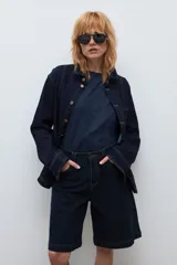 Bermuda de jean en color azul oscuro, con corte recto y largo hasta la rodilla. Presenta costuras a la vista en tono contrastante, cierre frontal con botón y bolsillos laterales.