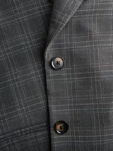 Blazer de sarga con diseño oversize, cuello con solapas y cierre frontal de dos botones. Presenta un estampado de cuadros en tonos gris oscuro y una estructura definida.