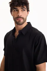 Camisa de manga corta negra, de corte clásico y cuello camisero.