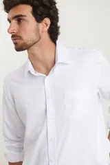 Camisa de vestir para hombre, color azul claro, de manga larga y cuello italiano. Tejido texturado y suave, confeccionada en una mezcla de algodón y poliéster.