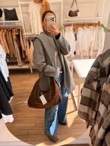 Cartera tipo hobo de diseño relajado, confeccionada en material con textura simil gamuza color chocolate. Presenta una silueta suave, cierre superior y asa corta combinada en simil cuero al tono.