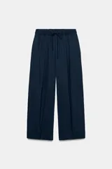 Pantalón de tiro medio con pierna ancha, confeccionado en mezcla de lyocell y viscosa. Cuenta con cintura elástica ajustable con cordones y bolsillos laterales ocultos en la costura.