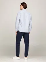 Camisa de corte regular confeccionada en algodón Oxford, con diseño de rayas verticales en tonos blanco y azul. Presenta cuello con botones, puños redondeados y logo de la marca bordado en el pecho.