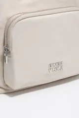 Bolso tipo tote y bandolera de color beige, con bolsillos externos con cierre y asas de mano y hombro.