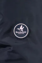 Campera de nylon color azul marino con cierre frontal completo, capucha desmontable y puños elásticos. Presenta bolsillos con cierre y logo aplicado en la manga.