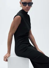 Vestido midi negro sin mangas, con cuello asimétrico y diseño entallado con detalle drapeado en la cintura.