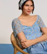 Blusa cropped de tule celeste con estampado floral, escote corazón, mangas cortas sueltas con acabado frufru y fruncido en el busto.