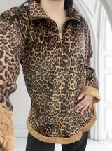 Buzo de micropana con estampado animal print, cuello polo con cierre de cremallera metálica dorada y puños y ruedo con ribete de corderito color beige.