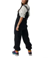 Mono de poliéster negro con textura de polar, tirantes ajustables con logo y hebilla, bolsillos delanteros y traseros con cierre.