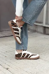 Zapatillas de estilo retro con diseño de paneles, combinando cuero beige con estampado animal print de leopardo y detalles en blanco. Presentan suela de goma color caramelo y cierre con cordones.