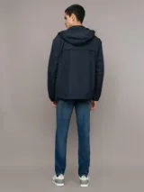 Campera rompeviento Calvin Klein de color azul marino, con cierre frontal de cremallera, capucha ajustable y bolsillos laterales. Presenta un parche con el logo de la marca en la manga y puños elásticos.