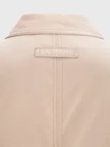 Campera Tommy Hilfiger color beige con cierre de cremallera, cuello doblado y dos bolsillos laterales. Tiene detalles distintivos de la marca y el logo bordado en el pecho.