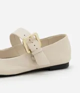 Zapatilla chatita de cuero color crema, con punta redonda, plantilla cómoda y tira con hebilla dorada en la parte superior.