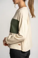 Sweater color crema con una franja horizontal verde en el pecho, de corte oversize y mangas largas.