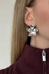 Aro de metal plateado con diseño de flor de cinco pétalos con acabado irregular y brillante.