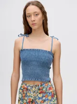 Top crop de tela denim con efecto fruncido, breteles finos ajustables con lazos y diseño entallado al cuerpo.