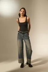 Pantalon jean de corte recto y tiro medio, con un lavado desgastado y un dobladillo ancho en la parte inferior que deja ver el revés de la tela con costuras en contraste.