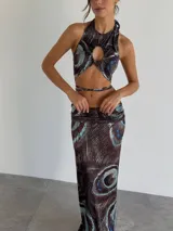 Top halter con estampado abstracto en tonos marrones y celestes, con abertura circular en el centro del pecho y lazos finos para atar en el cuello y la espalda.