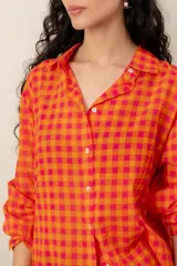 Camisa de manga larga con estampado tropical, fondo a rayas celestes y blancas, cuello camisero y cierre frontal de botones.