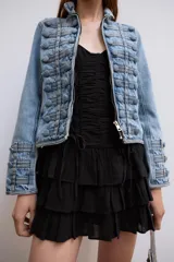 Vestido corto negro de tirantes finos ajustables y escote en V. Presenta un diseño ajustado con drapeado central y cordones cruzados laterales tipo corsé, y falda corta con tres capas de volantes escalonados.