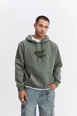 Canguro oversize de algodón con capucha y cordones ajustables. Presenta un diseño de estampa frontal con la frase 'GREAT TIMES' en relieve y bolsillo frontal tipo canguro.