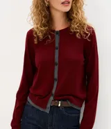 Cardigan de punto Marfinno, color negro con detalles en blanco en la botonera y el ruedo. Presenta cuello redondo, mangas largas y cierre frontal con botones oscuros.