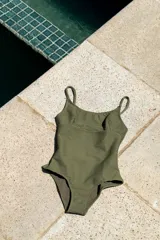 Traje de baño entero color verde oliva, con escote en U, tiras finas ajustables y corte bajo el busto. Presenta textura acanalada horizontal.