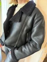 Campera de gamulán color marrón chocolate, con interior y detalles en corderito al tono. Presenta cierre frontal cruzado, cuello solapa amplio y bolsillos laterales con cierre metálico.