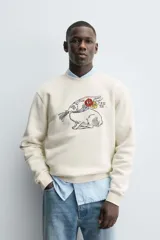 Sudadera de cuello redondo y manga larga con calce relajado. Presenta un bordado frontal de un conejo con flores y detalles en contraste, con terminaciones en rib en puños y ruedo.