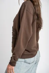Sweater marrón de algodón con cuello redondo y diseño de moños en relieve bordados en el frente.