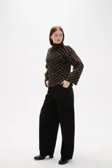 Sweater de tejido jacquard con diseño geométrico de líneas entrelazadas en tonos negro y marrón. Presenta cuello alto, mangas largas con terminación holgada y un corte recto.