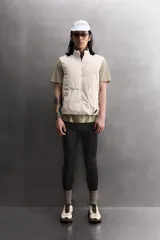 Chaleco técnico de corte regular con cuello subido y cierre frontal de cremallera. Presenta un diseño ligero con panel frontal ligeramente acolchado, bolsillos laterales con cremallera oculta y un bolsillo adicional en el pecho con tirador en color naranja. Incluye acabados con cinta elástica en el bajo y detalle de logo estampado.