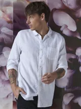 Camisa blanca de manga larga con cuello camisero, cierre frontal de botones y un bolsillo aplicado en el pecho.