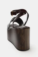 Sandalia de plataforma con taco alto corrido en bloque efecto madera, capellada de tira ancha y tira ajustable al tobillo con hebilla metálica dorada.