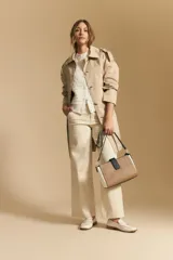 Chaleco tejido sin mangas color blanco roto, con cuello redondo y cartera frontal de botones. Presenta un punto calado con textura.