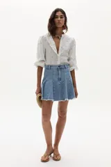 Minifalda de denim con diseño plisado y ruedo desflecado, de tiro medio y calce ajustado.