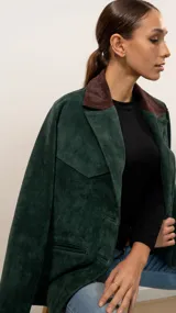 Blazer de gamuza color verde pino con cuello de solapa en color marrón chocolate. Presenta cierre frontal de un botón, bolsillos laterales y forro interior.