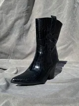 Bota texana negra de caña media con estampado símil piel de cocodrilo y taco cónico.