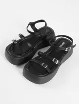 Sandalias negras con plataforma, tiras finas y hebillas metálicas ajustables.