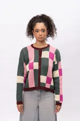 Saco de punto con diseño geométrico de cuadros en tonos verde, rosa, fucsia y crema. Presenta cuello redondo, cierre frontal con botones y terminaciones en color bordó.
